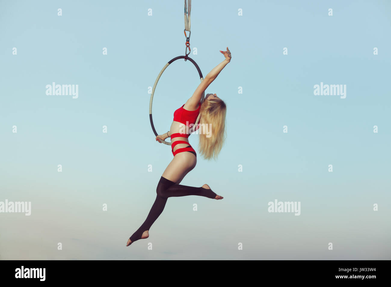 Female acrobat while presenting the show in the air on the hoop. Stock Photo