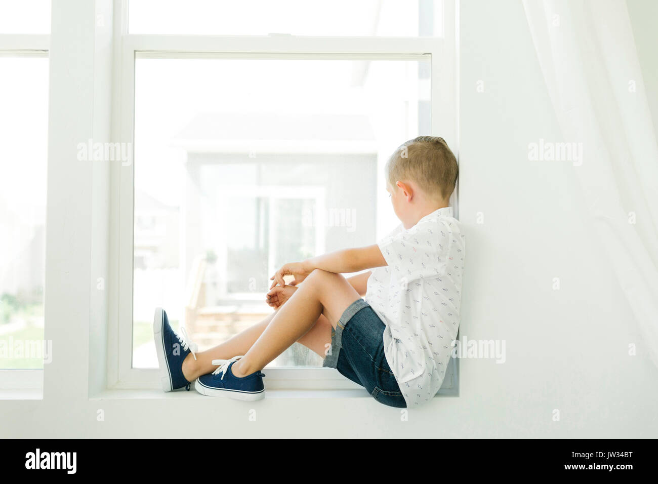 Boy (7-8) looking through window Stock Photo