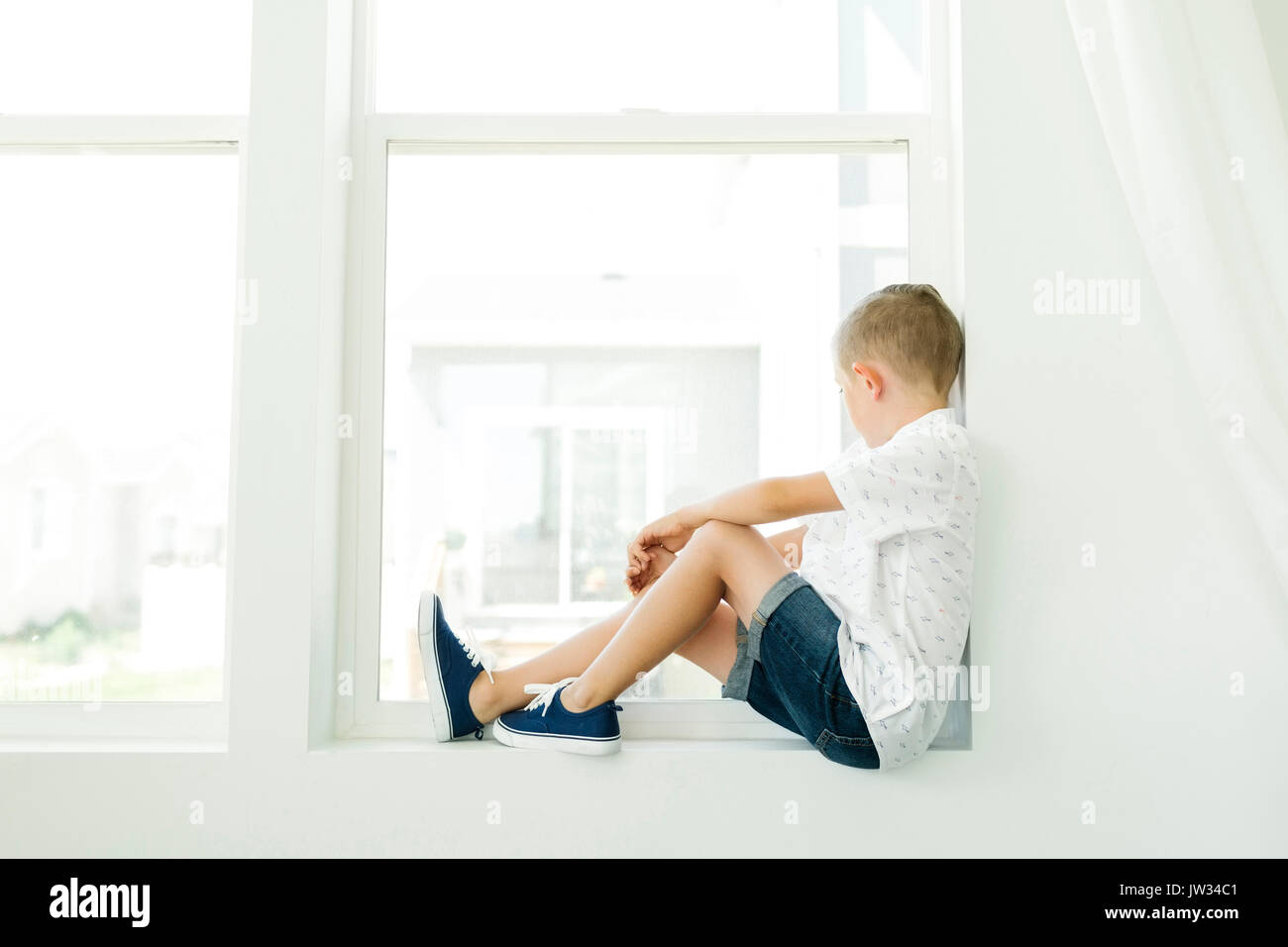 Boy (7-8) looking through window Stock Photo