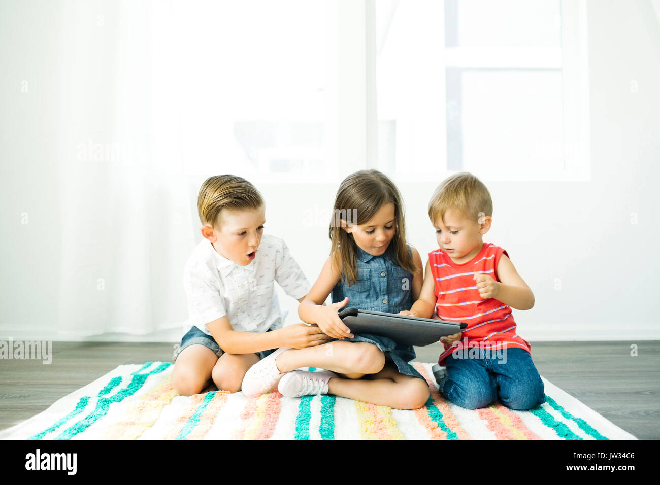 Siblings (2-3, 6-7) using digital tablet at home Stock Photo