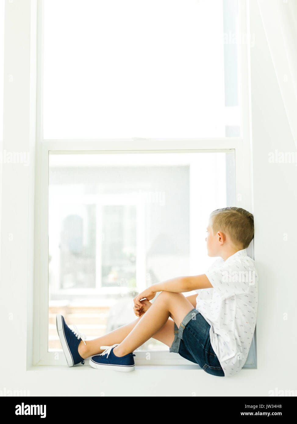 Boy (6-7) looking through window Stock Photo