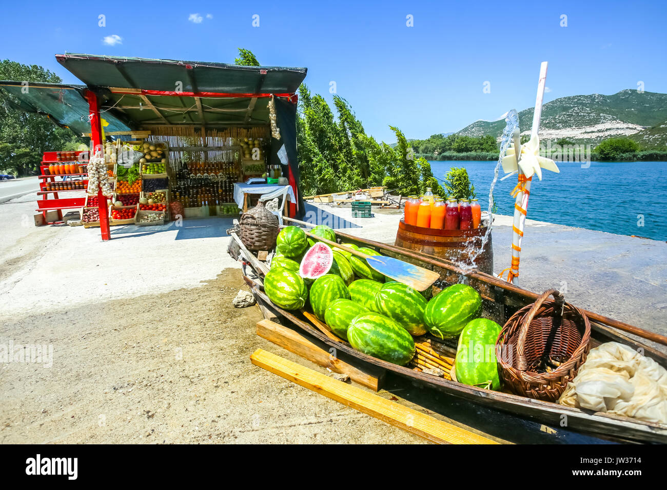 Watermelons in a boat and fresh homemade fruit juices on a barrel displayed at a food stand next to the river Neretva in Croatia. Stock Photo