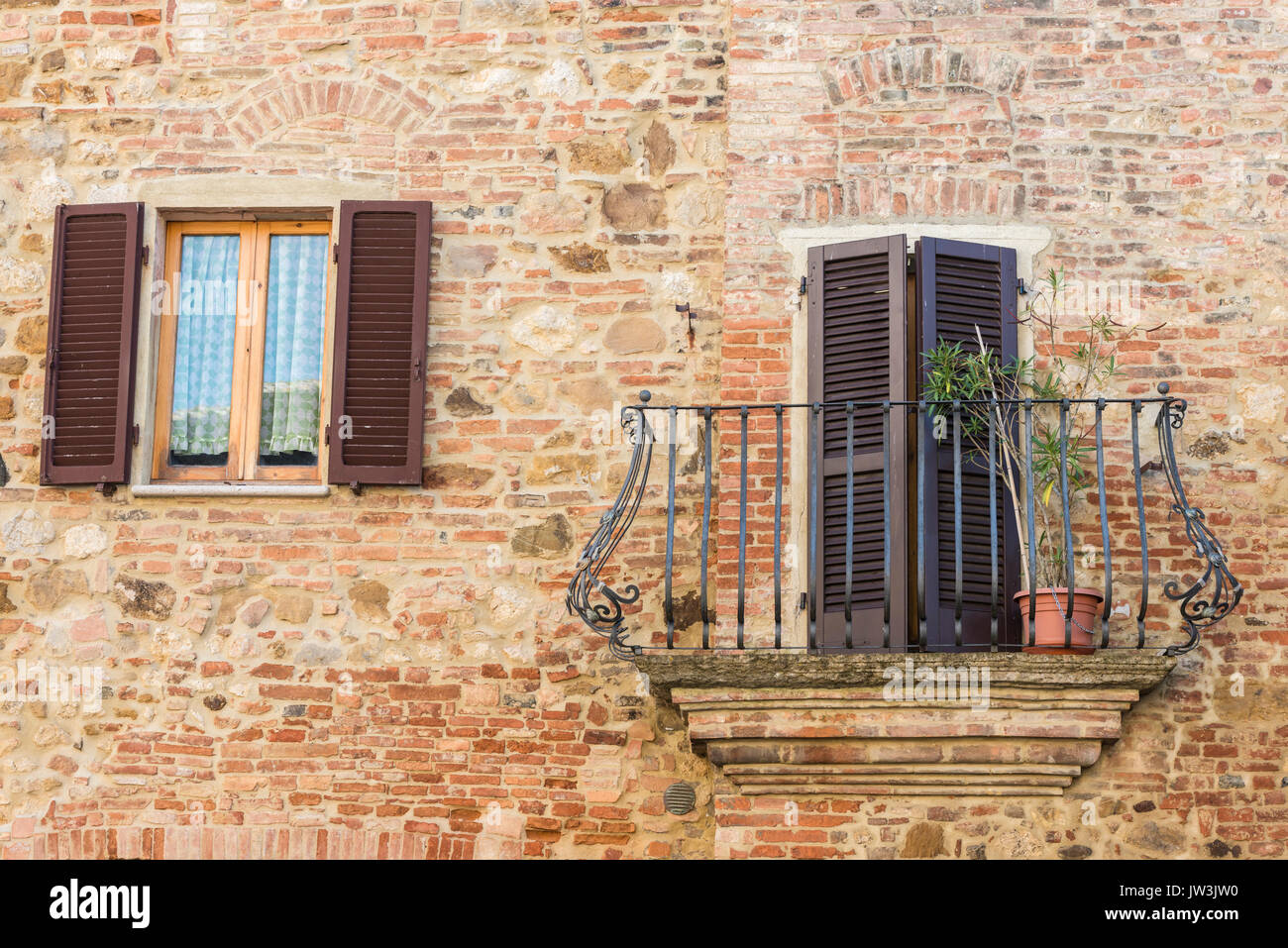 Italy, Tuscany, Montepulciano, Stony and brick facade of house with carved metal balcony and latticed sun blinds Stock Photo