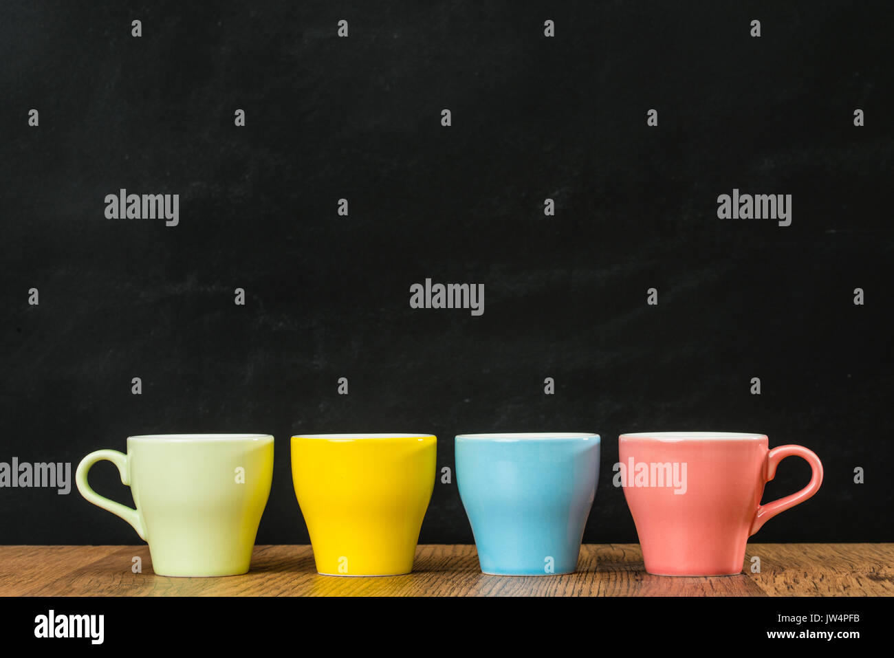 warm color coffee cups show the spring season style on wood texture floor table with chalk blackboard wall background with milky white yellow blue pin Stock Photo