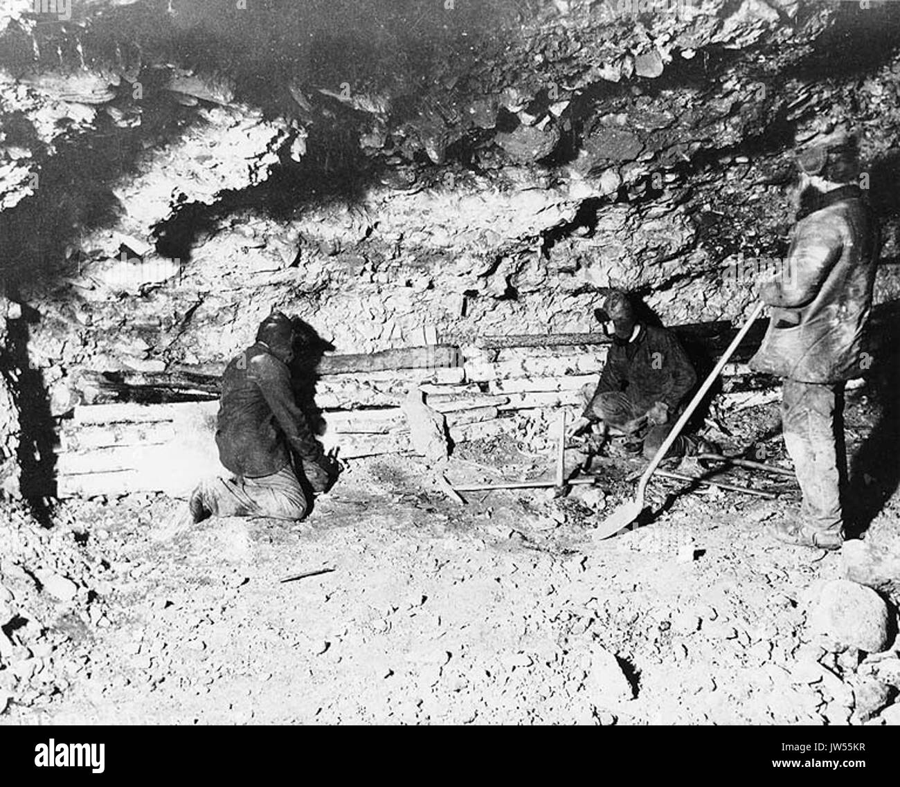 Three miners in underground gold mine, probably Yukon Territory, ca