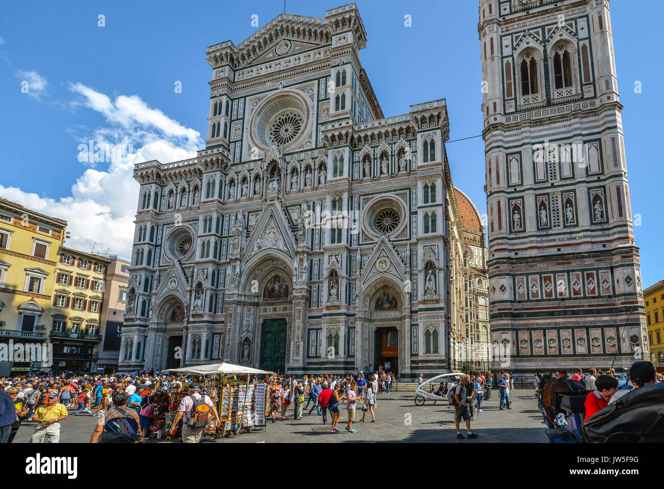 The duomo, Florence Cathedral and Giotto's Campanile in the Piazza del Duomo in the historic center of Florence Italy with tourists and souvenir stand Stock Photo