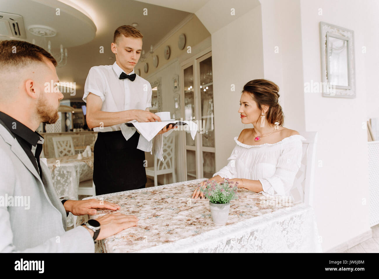 waiter brought cup of coffee for beautiful couple in a cafe Stock Photo