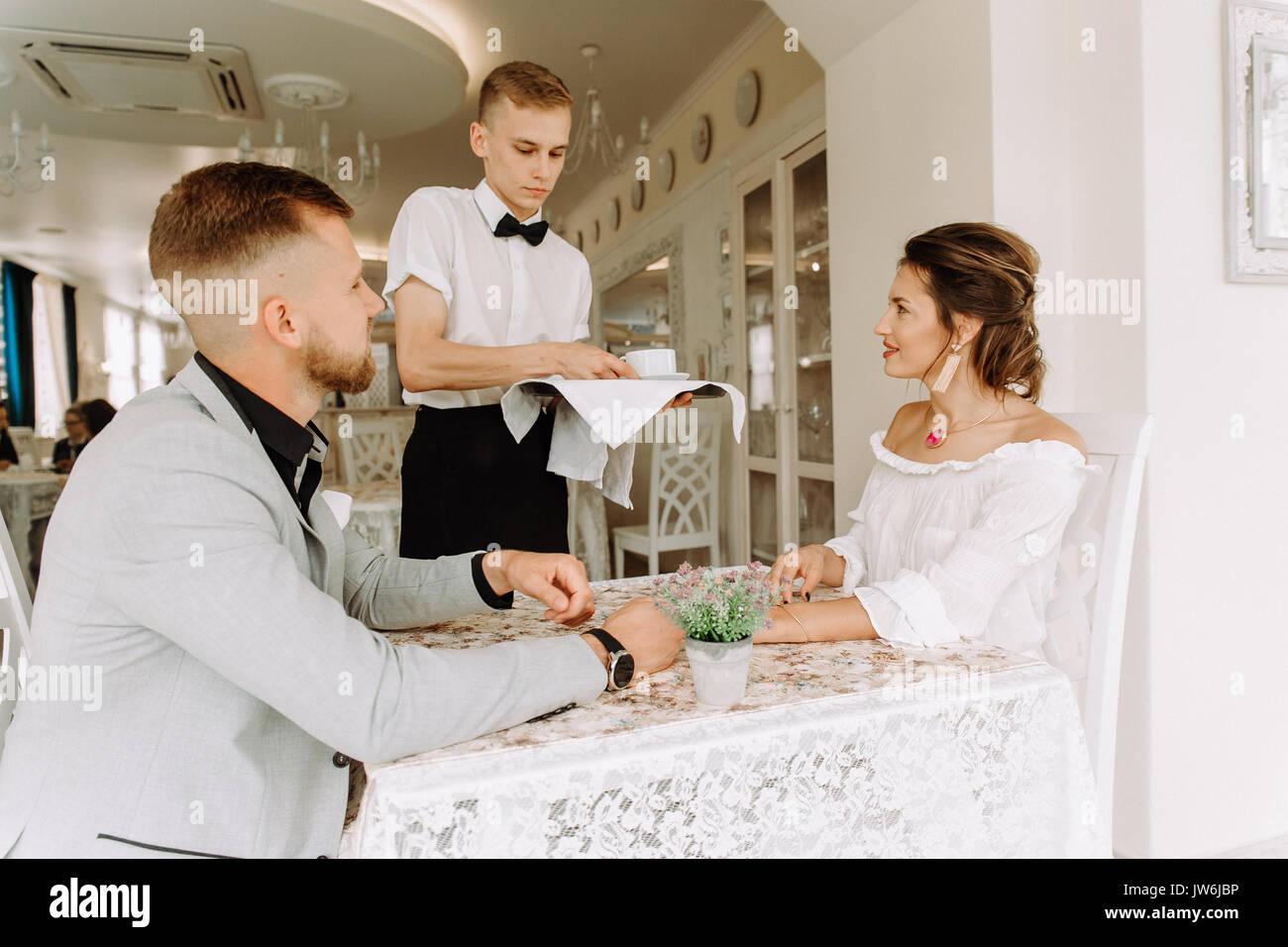 waiter brought cup of coffee for beautiful couple in a cafe Stock Photo