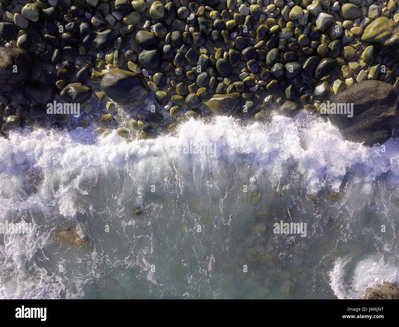 Aerial over waves crashing into a rocky beach Stock Photo