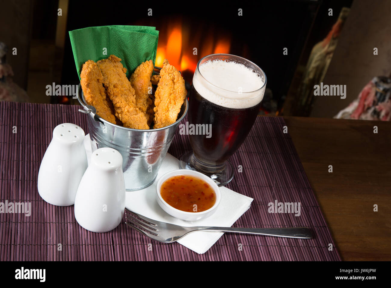 A pub/restaurant lunch/ snack of Hot and Spicy breaded Chicken fillets with a Sweet Chili dip and a glass of ale. Stock Photo