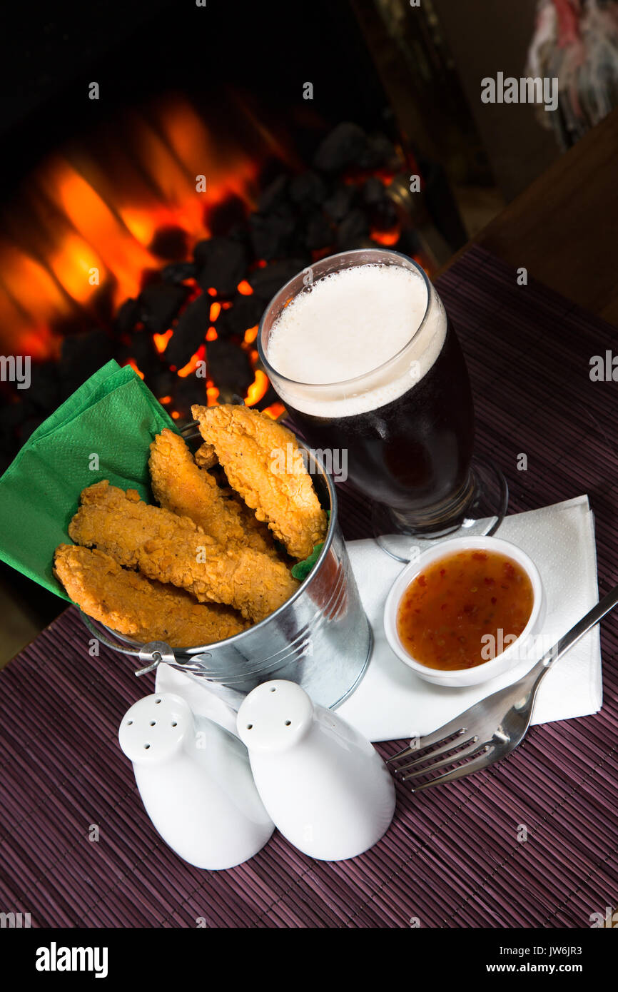 A pub/restaurant lunch/ snack of Hot and Spicy breaded Chicken fillets with a Sweet Chili dip and a glass of ale. Stock Photo