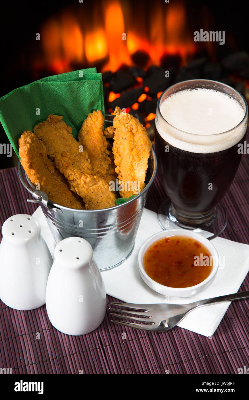 A pub/restaurant lunch/ snack of Hot and Spicy breaded Chicken fillets with a Sweet Chili dip and a glass of ale. Stock Photo