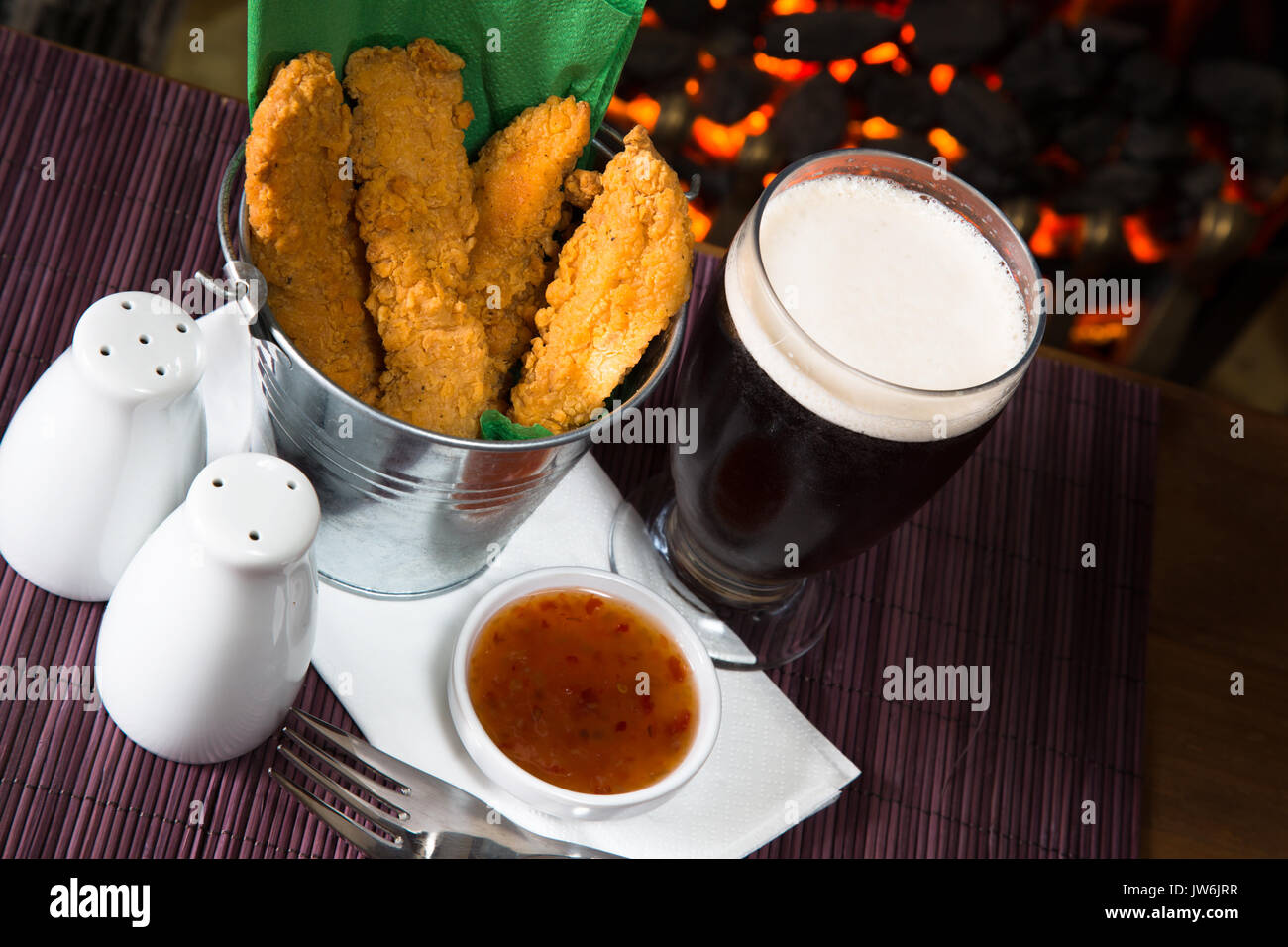 A pub/restaurant lunch/ snack of Hot and Spicy breaded Chicken fillets with a Sweet Chili dip and a glass of ale. Stock Photo