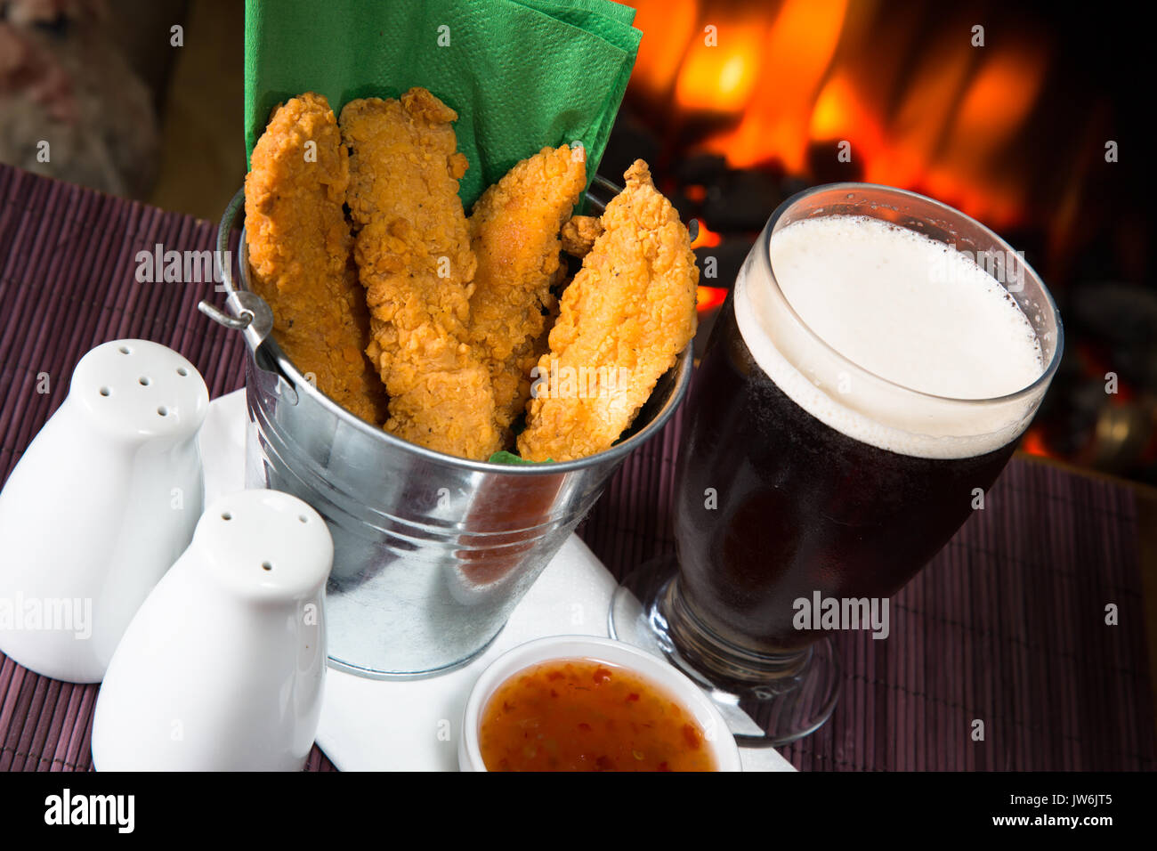 A pub/restaurant lunch/ snack of Hot and Spicy breaded Chicken fillets with a Sweet Chili dip and a glass of ale. Stock Photo