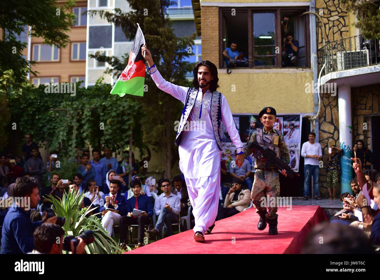 Kabul, Afghanistan. 10th Aug, 2017. Fashion show organizer Ajmal Haqiqi waves a national flag during the show in Kabul, Afghanistan, on Aug. 10, 2017. More than 20 models including six girls attired in colorful dress attended the catwalk ceremony in Kabul on Thursday to display costumes of ethnic people living in Afghanistan. This is the third time that fashion show was held in the conservative society over the past decade, where Taliban-led militancy is continuing. Credit: Dai He/Xinhua/Alamy Live News Stock Photo