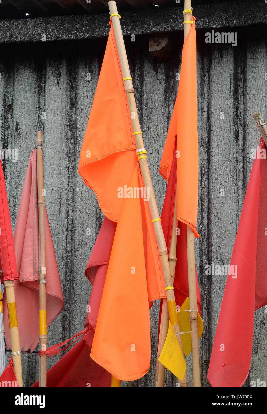 Red and orange marker flags for fishing net arranged on a wooden wall, ready fo rnext use. Stock Photo