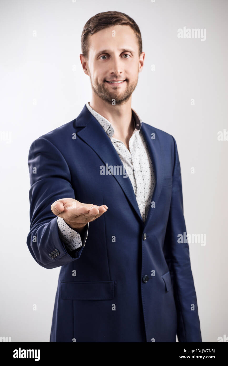 Man in business suit standing and shows outstretched hand with open palm. Stock Photo