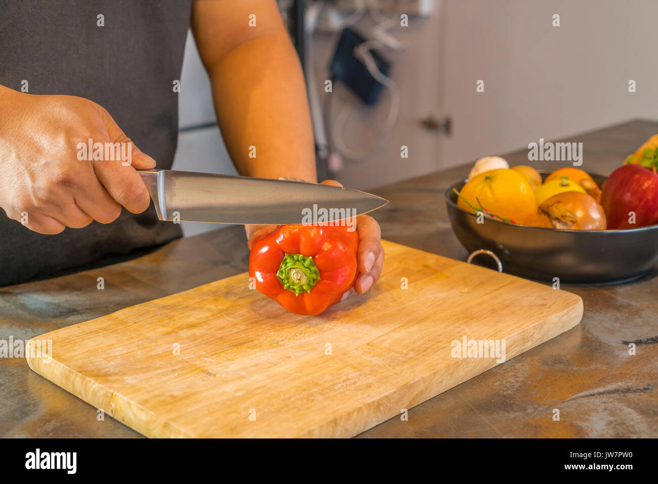 Chef cutting red bell pepper on wooden broad. Stock Photo