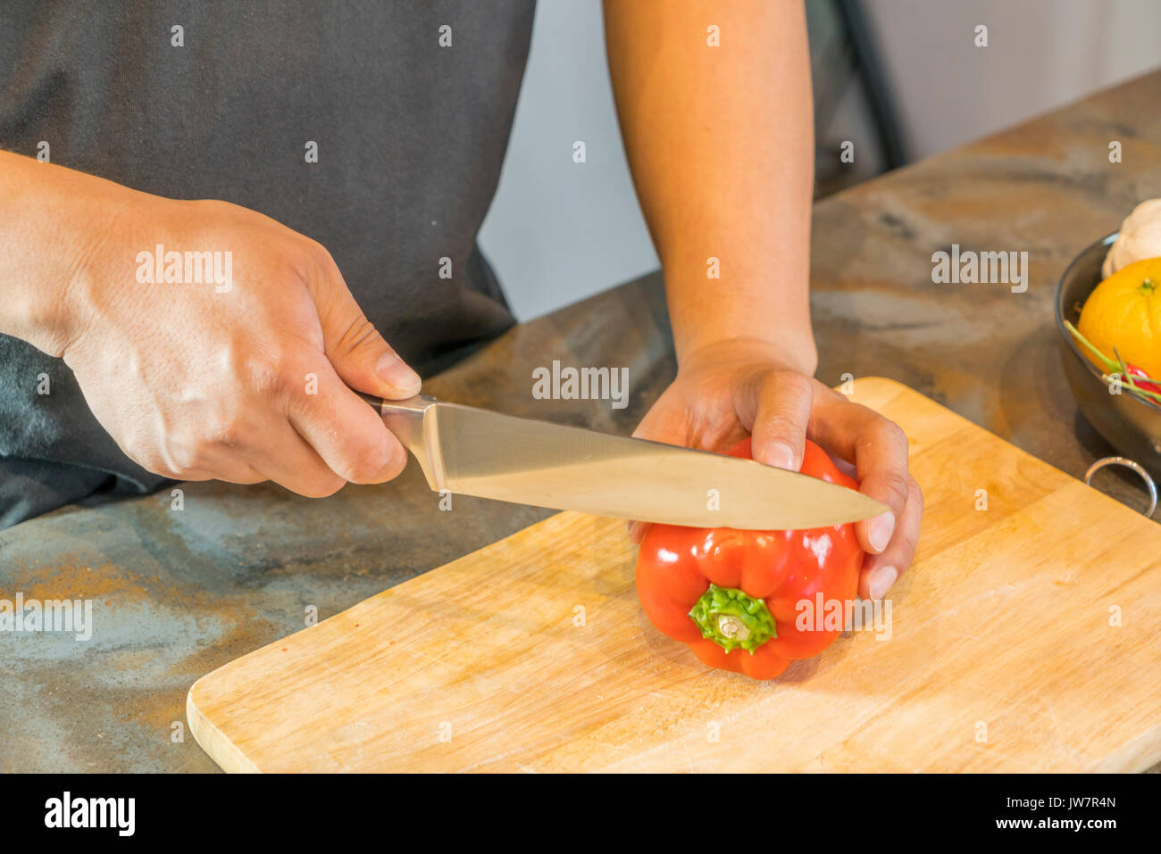 Chef cutting red bell pepper on wooden broad Stock Photo