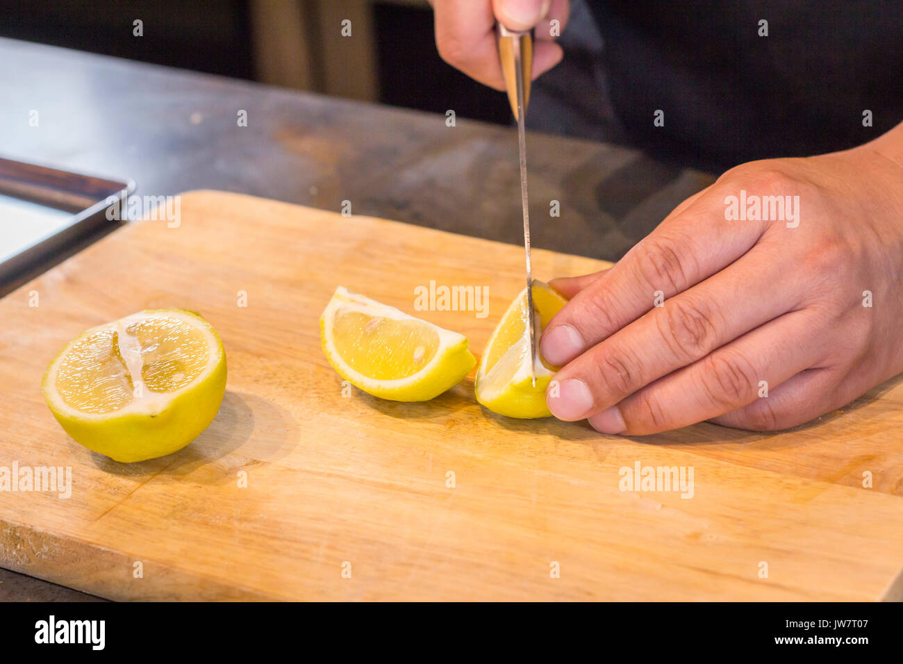 Chef slicing Lemon on wooden cutting board. Stock Photo