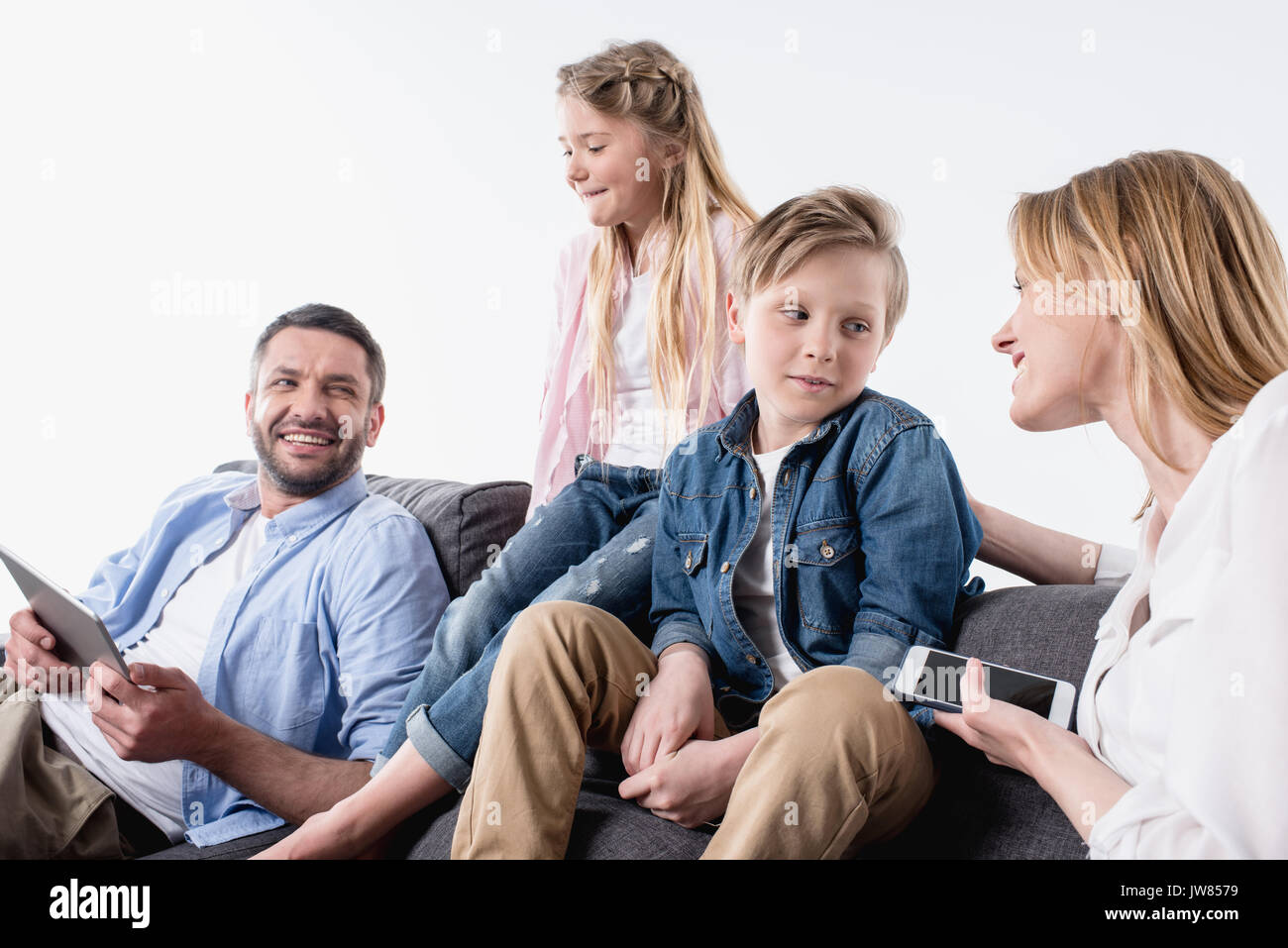 caucasian family with digital devices sitting on sofa together Stock Photo