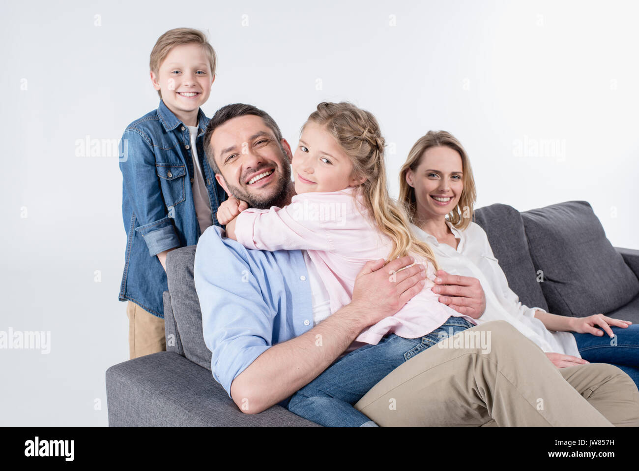 caucasian family looking at camera while sitting on sofa together isolated on white Stock Photo