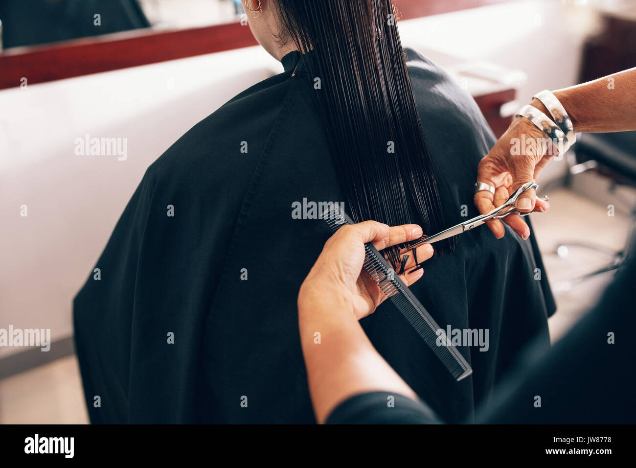 Hair stylist cutting the hair to a straight level. Hairdresser using