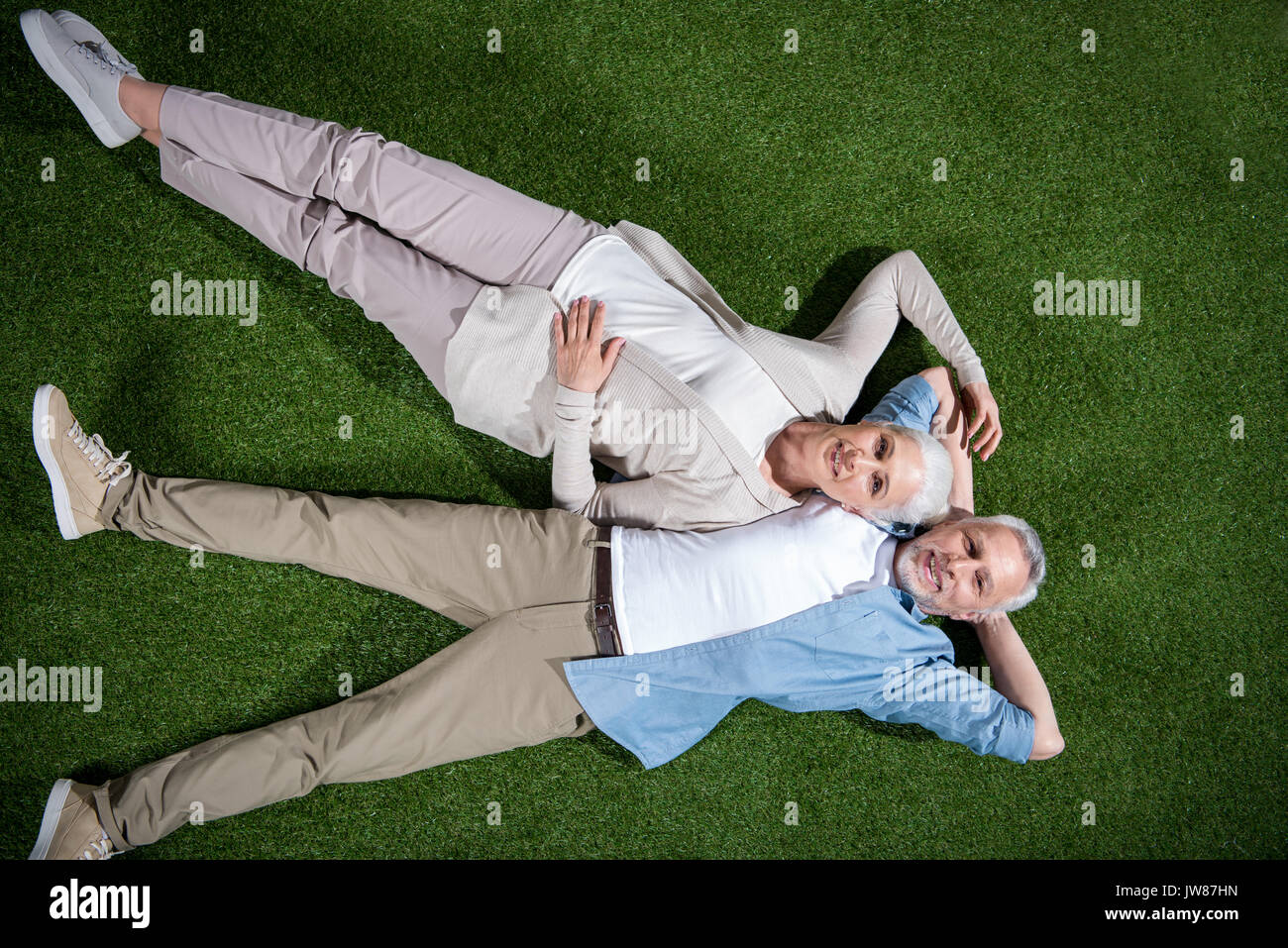 Top view of happy senior couple lying together on green grass and ...