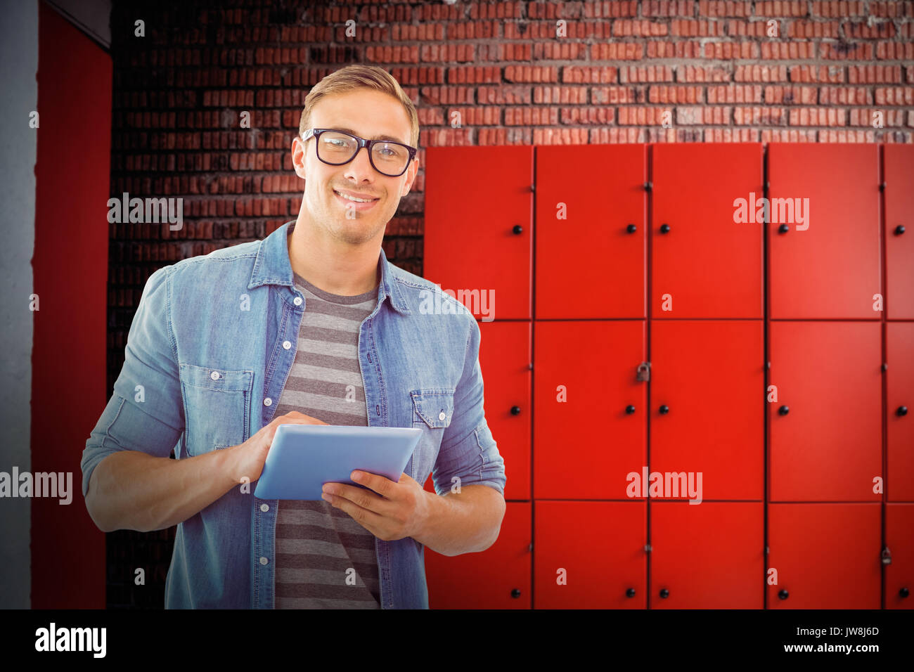 Student using tablet against orange lockers against brick wall Stock Photo