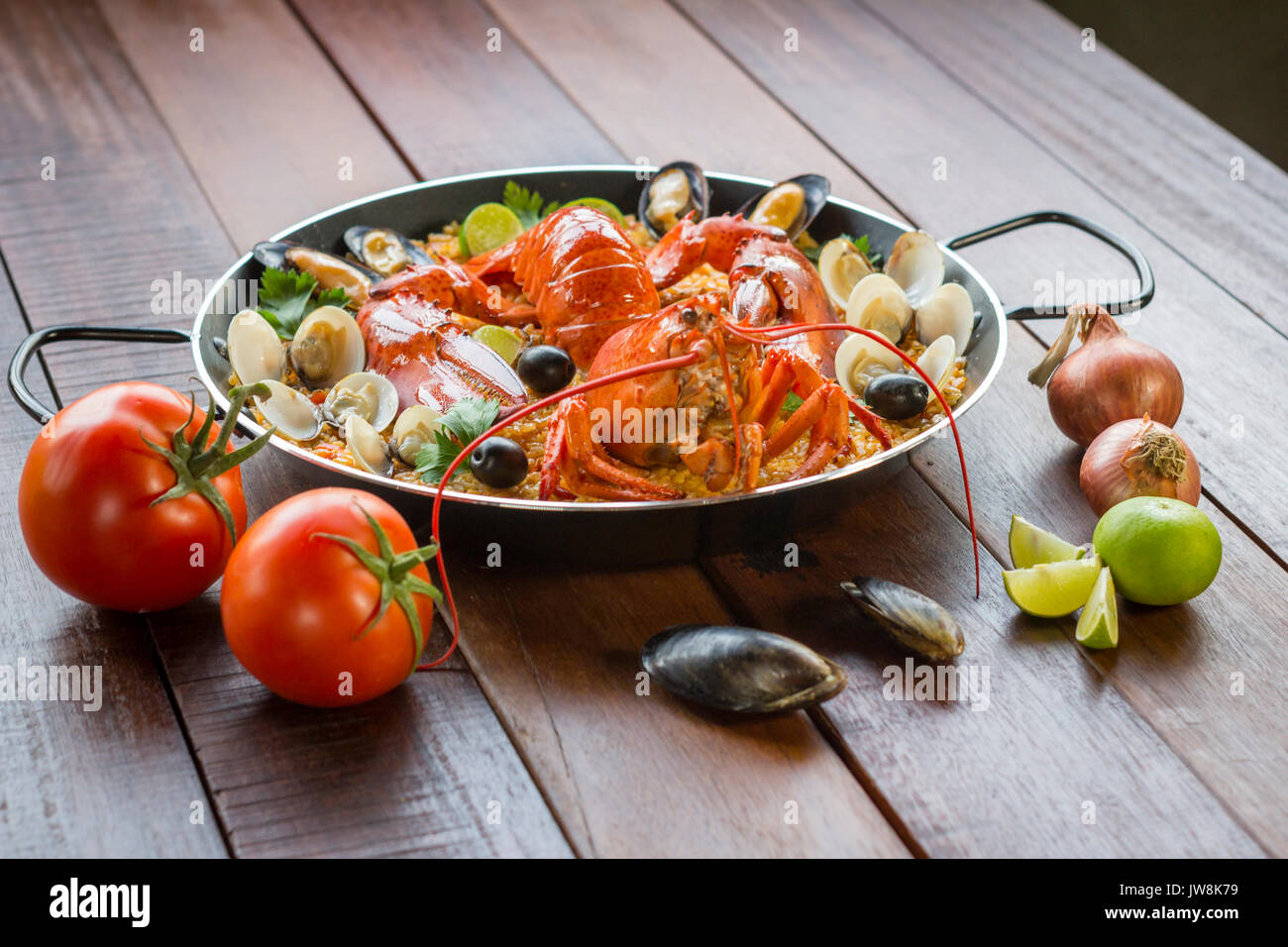 Gourmet seafood Valencia paella with fresh langoustine, clams, mussels and squid on savory saffron rice with peas and lemon slices, close up view Stock Photo