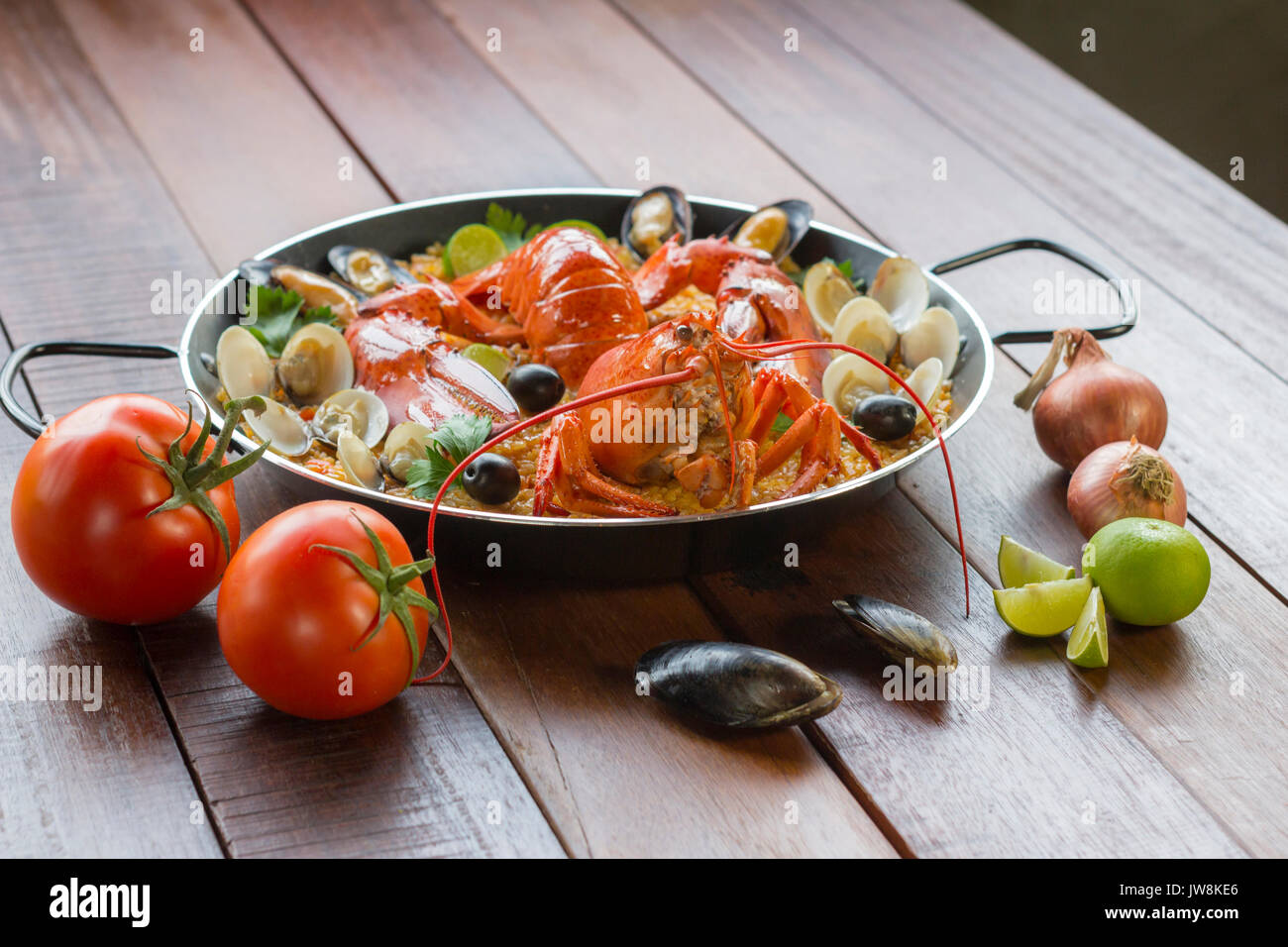 Gourmet seafood Valencia paella with fresh langoustine, clams, mussels and squid on savory saffron rice with peas and lemon slices, close up view Stock Photo