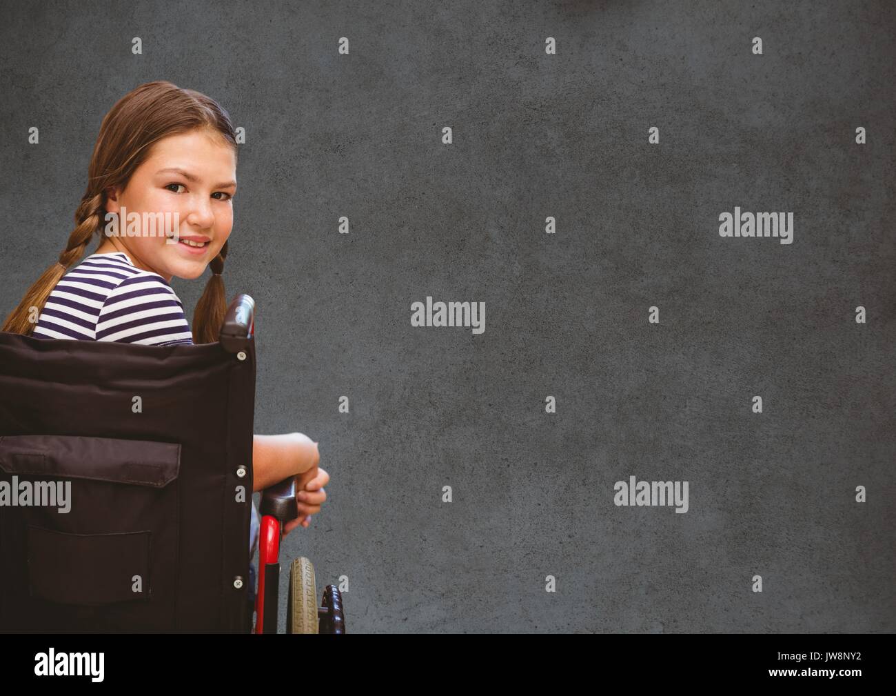 Digital composite of Disabled girl in wheelchair in front of blackboard Stock Photo