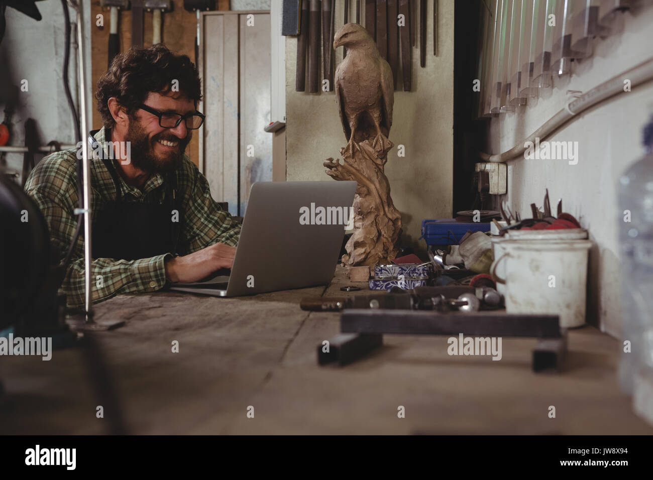 Smiling craftsman using laptop in workshop Stock Photo