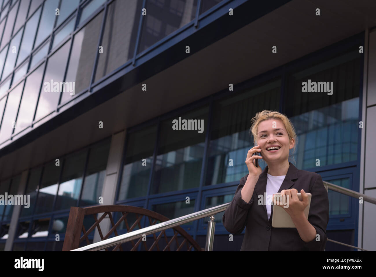Smiling university student talking on mobile phone in campus Stock Photo
