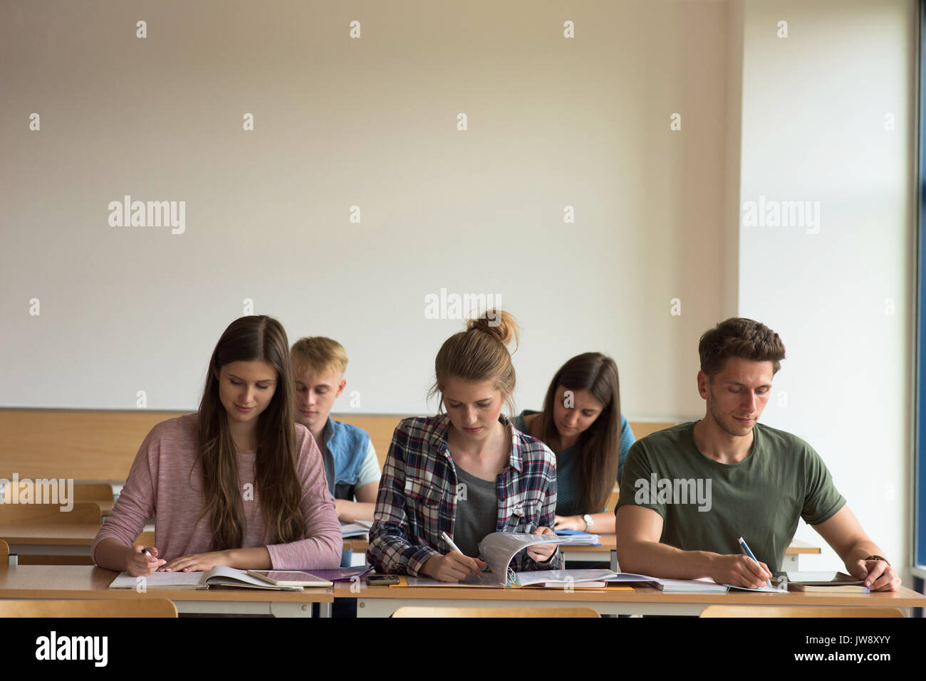 Students studying at desk in classroom Stock Photo