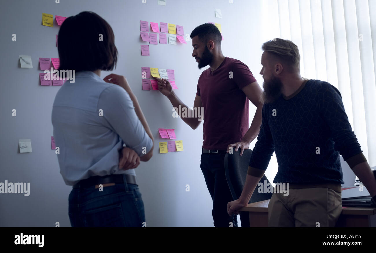Colleagues discussing over sticky notes in office Stock Photo