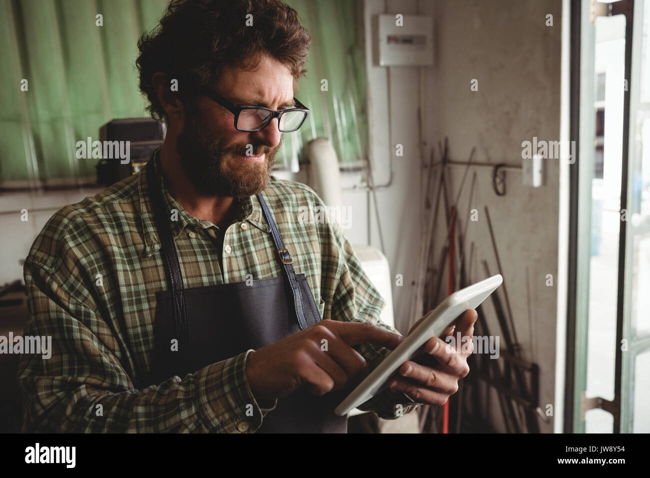 Attentive craftsman using digital tablet in workshop Stock Photo