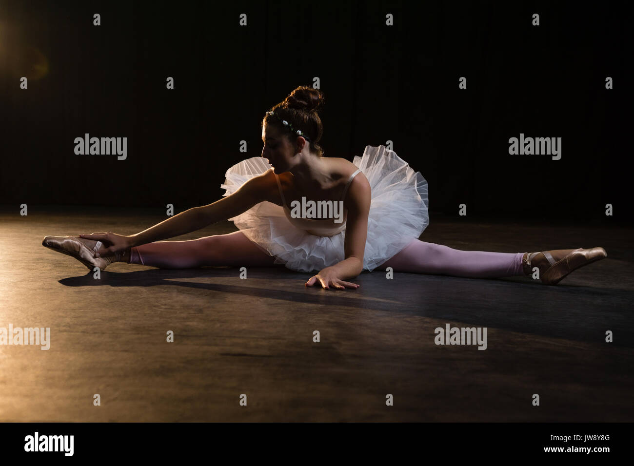 Female ballet dancer stretching before dancing in the studio Stock Photo