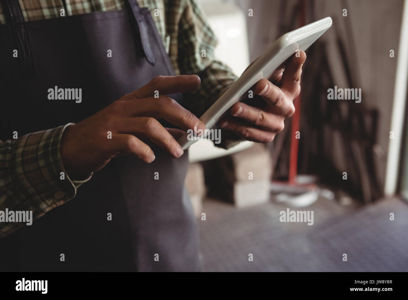 Mid-section of craftsman using digital tablet in workshop Stock Photo
