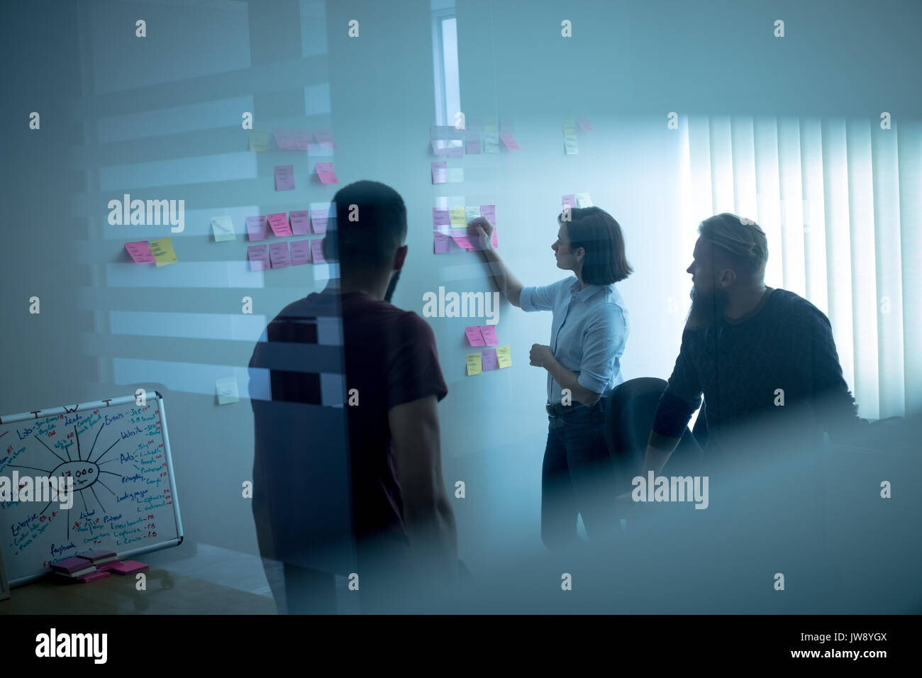 Colleagues discussing over sticky notes in office Stock Photo