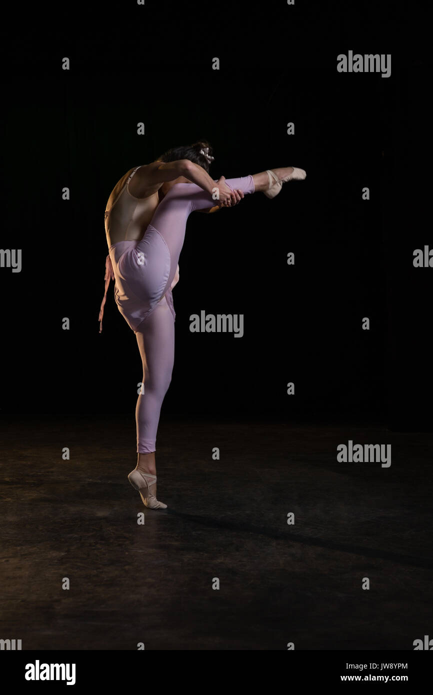 Ballet dancer posing on her tiptoe while rising a leg in studio Stock Photo