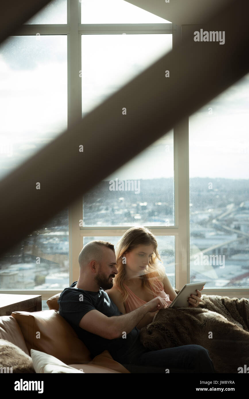 Romantic couple using digital tablet while lying on sofa at home Stock Photo