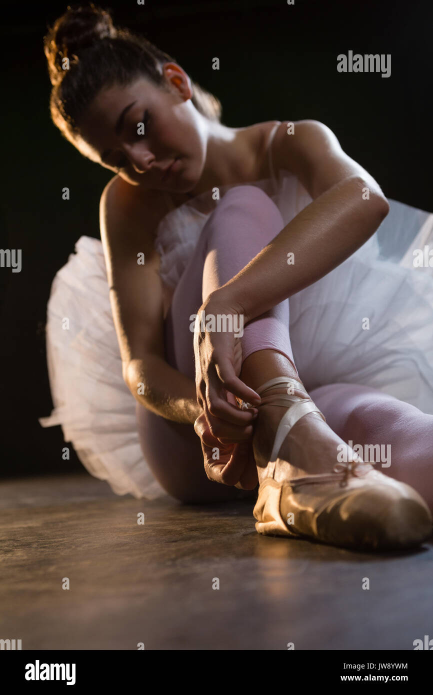Female ballet dancer tying the ribbon on her ballet shoes in the studio  Stock Photo - Alamy