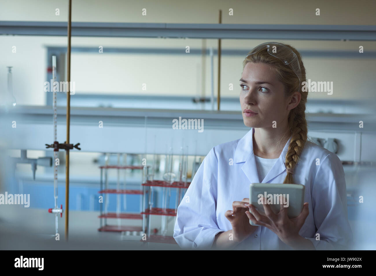 Thoughtful university student using digital tablet in laboratory Stock Photo