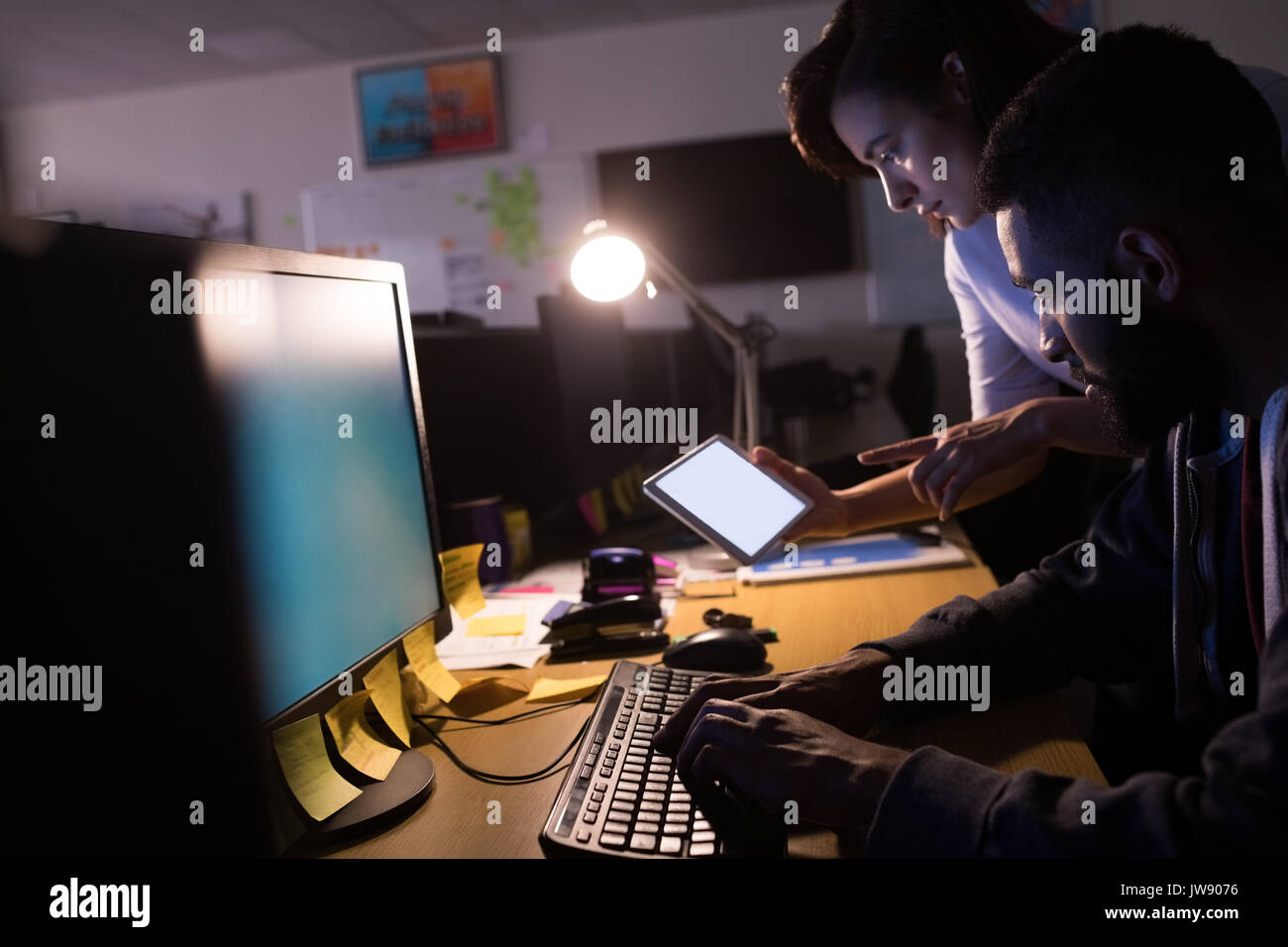 Colleagues using digital tablet while working at desk in office Stock Photo