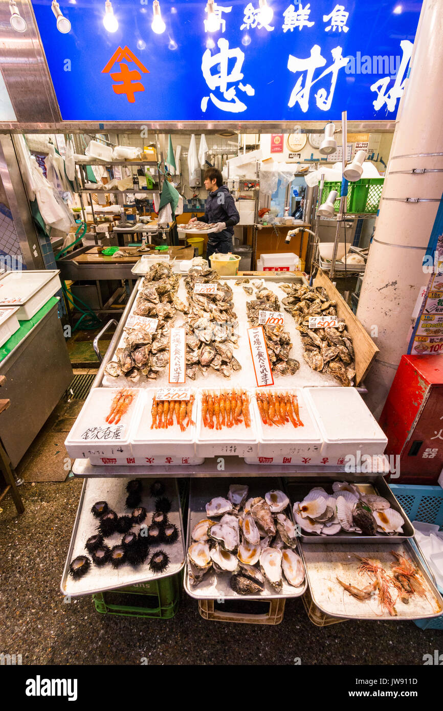 Fresh seafood stall with various types of clams and prawns with price labels on sale in the indoor market, Omicho, in Kanazawa, Japan. Stock Photo