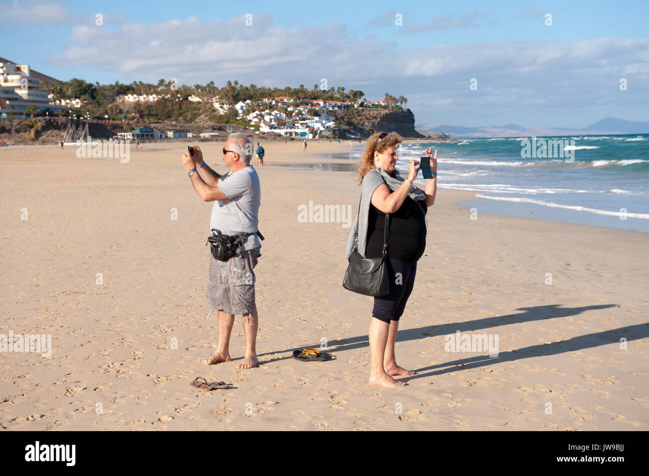 tourists taking photographs on a beach in jandia fuerteventura Stock Photo