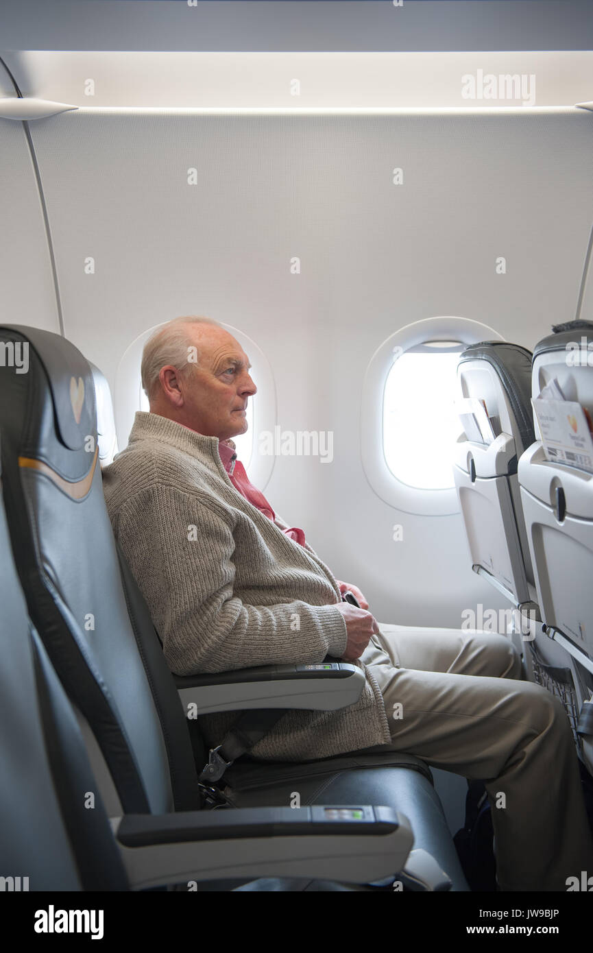 senior man travelling alone on an airplane Stock Photo