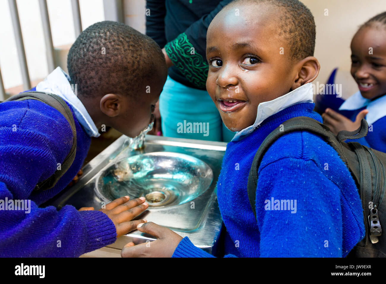 Young school children from Kibera drinking from water fountain in Kibera Town Centre, Nairobi, Kenya Stock Photo