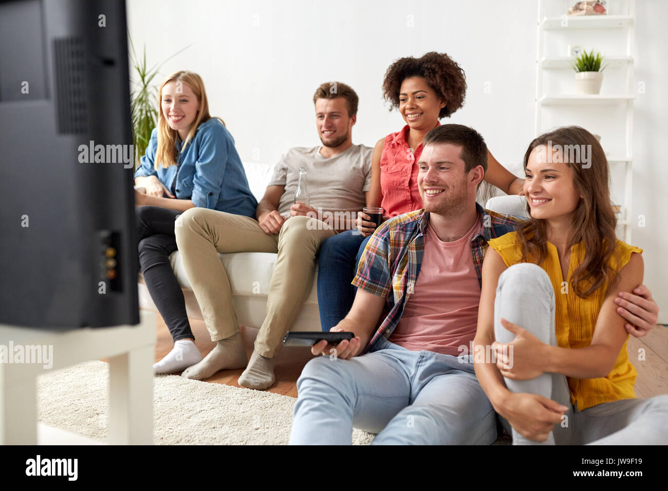happy friends with remote watching tv at home Stock Photo - Alamy
